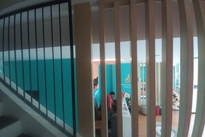 Interior de hotel com escadaria, balcão de recepção e vista da área de lobby.