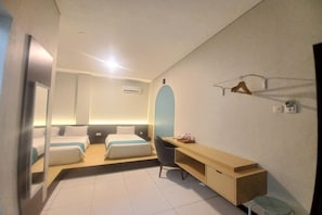 A hotel room with two beds, a desk, a chair, a mirror, and a wardrobe.