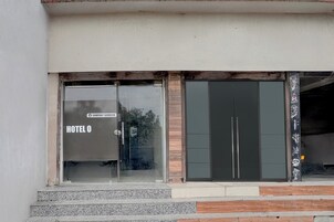 Entrada de un hotel con puerta de cristal que indica 'HOTEL O' y un cartel que dice 'SERVICIO DE LA EMPRESA'.