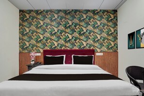 Una habitación de hotel con una cama, una mesita de noche, una silla y una pared con diseño de hojas.