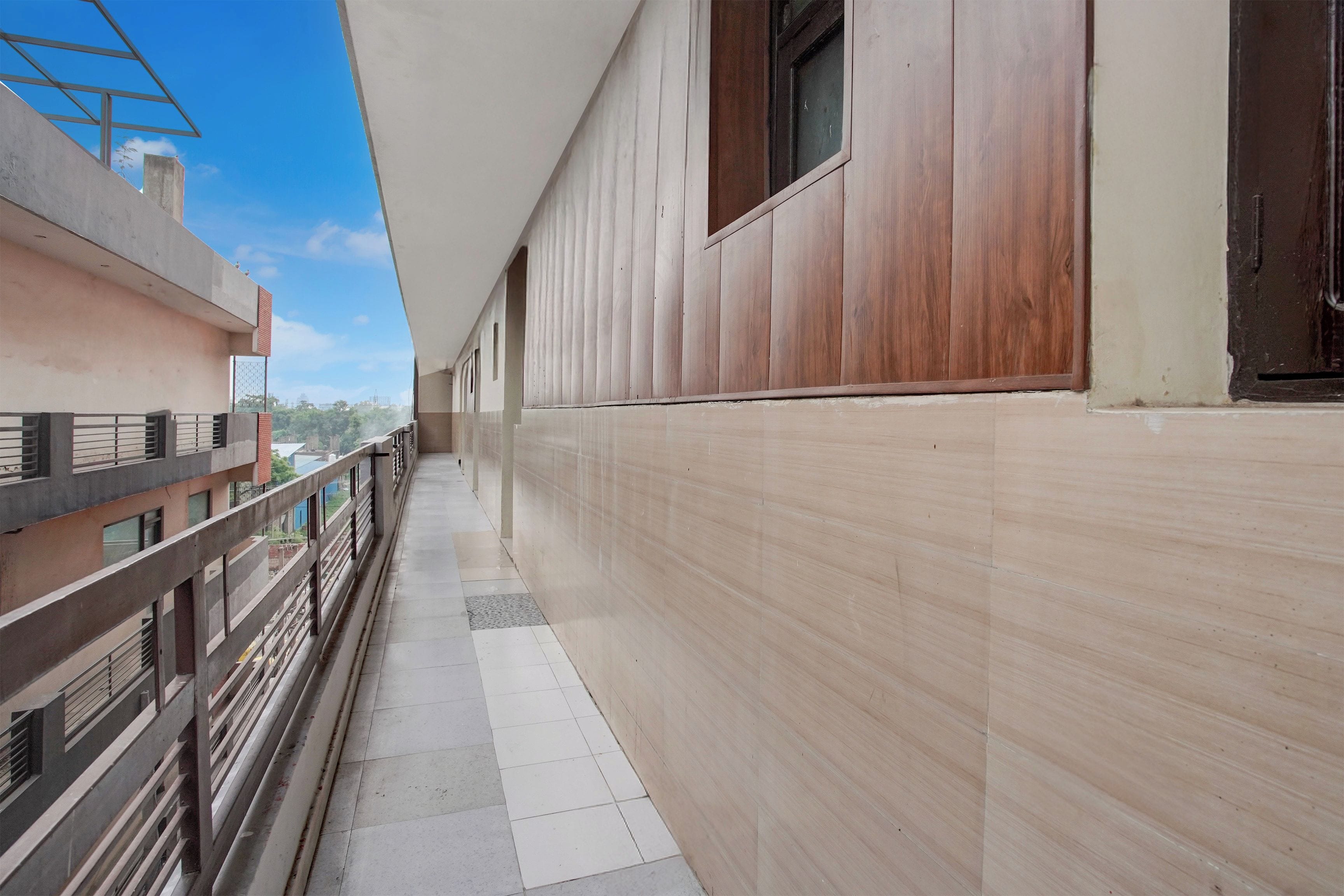 A corridor with a tiled floor, a wooden wall, and a metal railing on one side.