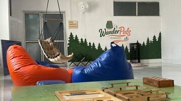 A room with a hammock chair, a wooden board game, and a wall mural.