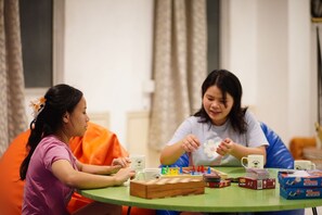 Two individuals seated at a round table with a board game, playing cards, and coffee mugs. - Wanderpals Guwahati (Guwahati)