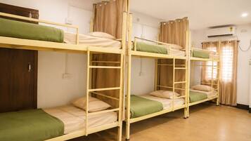 Quarto com beliches, guarda-roupa de madeira, ar condicionado e janela com cortinas.