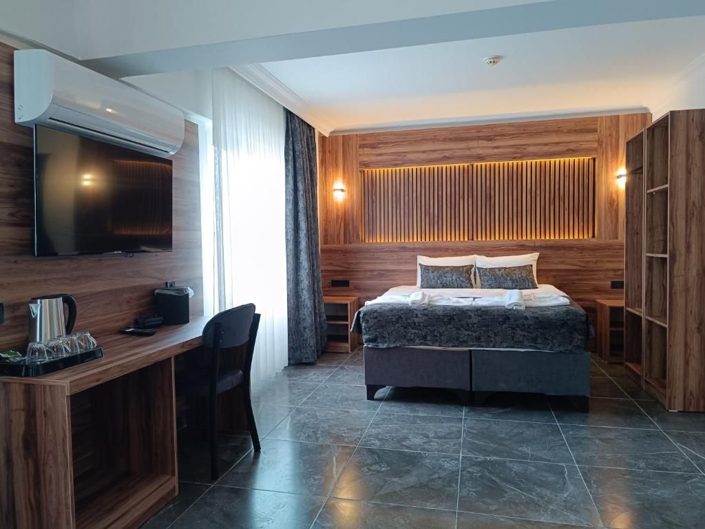Une chambre moderne équipée d’un lit, d’un bureau, d’une télévision et d’une armoire intégrée.