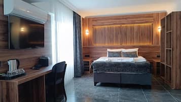 Une chambre moderne équipée d’un lit, d’un bureau, d’une télévision et d’une armoire intégrée.