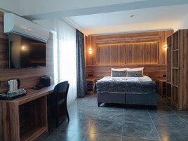 Un dormitorio moderno con cama, escritorio, televisor y armario empotrado.