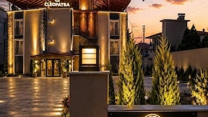 En hotelindgang med et skilt, der siger 'Cleopatra', omgivet af en veloplyst sti og grøntområder.
