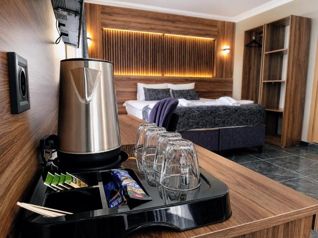 Ein Hotelzimmer mit Bett, Nachttisch und Tablett mit Gläsern und Snacks.