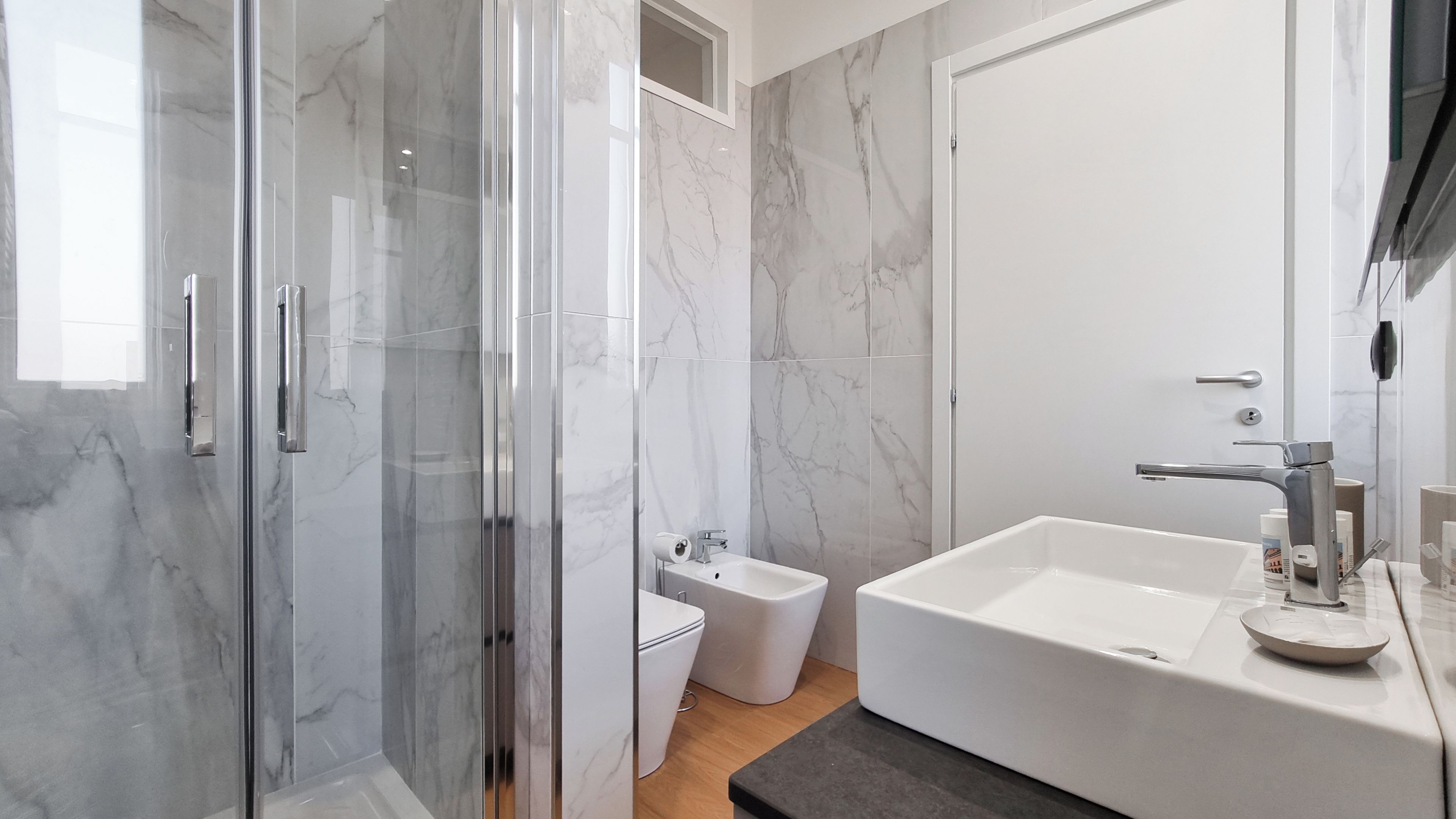 Une salle de bain moderne avec une douche à l’italienne en verre, des toilettes blanches et une grande baignoire.