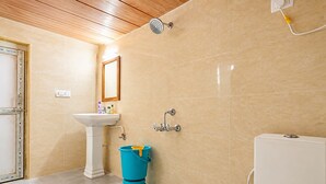 Et badeværelse med en hvid vask, et spejl, en bruseniche og et toilet.