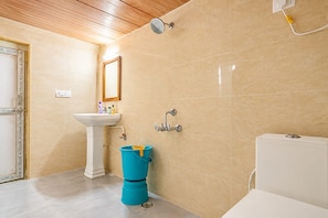 Une salle de bain avec un lavabo blanc, un miroir, une douche et des toilettes.