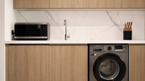 A kitchen with a microwave, sink, and washing machine. - Vanilla Homes Premium Studio Yas Golf Collection (Abu Dhabi)