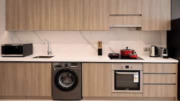 A modern kitchen with a washing machine, oven, microwave, and a coffee maker.