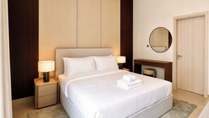 A hotel room with a bed, bedside lamps, a mirror, a desk, and a door. - Vanilla Homes Premium Studio Yas Golf Collection (Abu Dhabi)