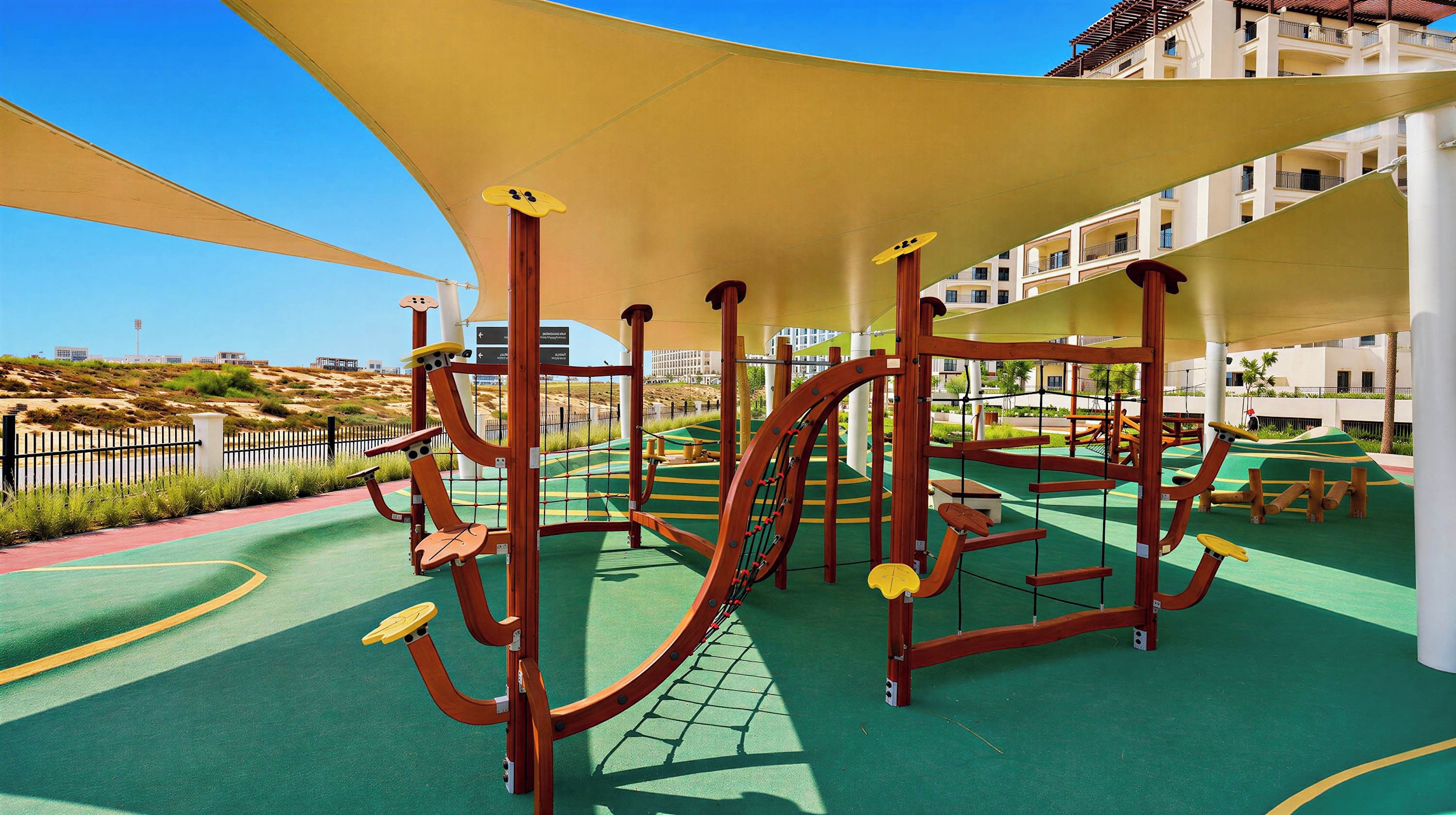 A playground with climbing structures and a covered area, surrounded by a landscaped garden and a building in the background.