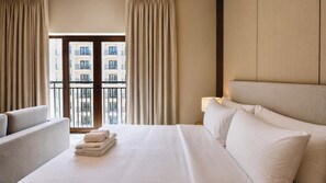 A hotel room with a bed, a chair, a nightstand with a lamp, and a view of a building through the window. - Vanilla Homes Premium Studio Yas Golf Collection (Abu Dhabi)