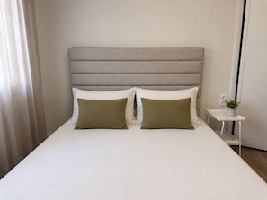 A bed with a headboard, two pillows, a bedside table with a plant, and a curtain. - Quiet City Studio w/ Kitchen near Ladadika (Thessaloniki)