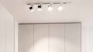 Casa de banho moderna com um amplo lavatório branco, sanita e guarda-roupa duplo com puxadores.