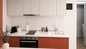 Cozinha moderna com armários brancos, fogão por indução preto, coifa de aço inoxidável e forno embutido.