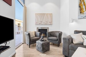 Un salon moderne avec des canapés gris, un téléviseur à écran plat et une cheminée.