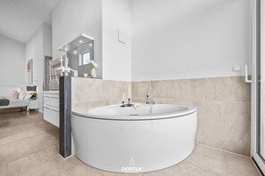 Un baño moderno con una bañera independiente grande, un tocador con espejo y un inodoro.