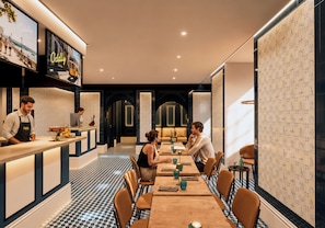 Un restaurante moderno con una larga mesa común, asientos individuales y una zona de bar.