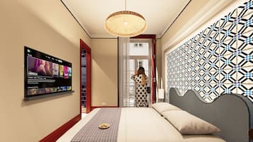 A hotel room with a bed, a wall-mounted TV displaying a movie, and a patterned wall.