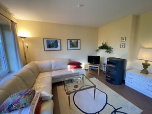 A living room with a sofa, a glass coffee table, a television, a fireplace, and a lamp. - Dünenzauber – Your Relaxing Getaway at Schönberger Strand (Schönberg (Holstein))