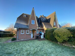 A two-story house with a brick facade, a pitched roof, and a small front porch. - Dünenzauber – Your Relaxing Getaway at Schönberger Strand (Schönberg (Holstein))