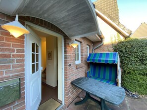 A brick house with a covered porch, a bench, and a door leading inside. - Dünenzauber – Your Relaxing Getaway at Schönberger Strand (Schönberg (Holstein))