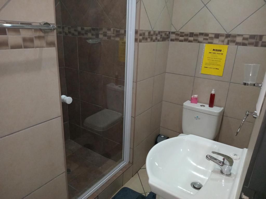 Un baño con cabina de ducha de vidrio, un lavamanos blanco y un inodoro.