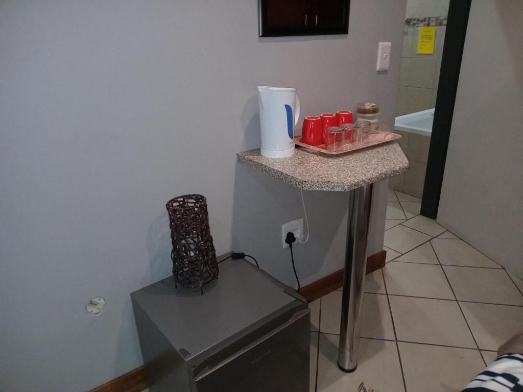 A kitchenette with a coffee maker, red cups, and a small refrigerator.