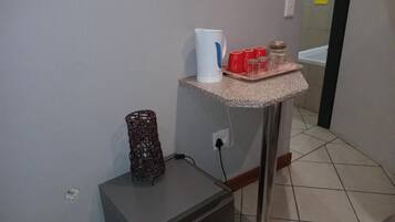 A kitchenette with a coffee maker, red cups, and a small refrigerator.