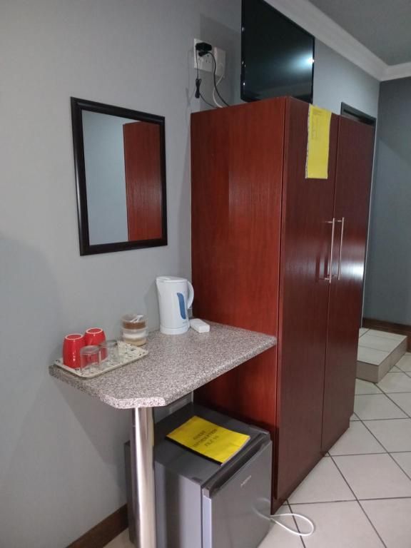 Una kitchenette con una encimera, una cafetera y un refrigerador pequeño.