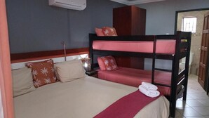 A bunk bed with a red and beige bedspread, a wooden headboard, and a red towel on the footboard. - Grand Central Guesthouse (Rustenburg)