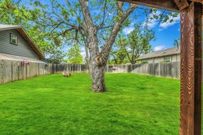 Ein Garten mit Holzzaun, Baum und Rasenfläche.