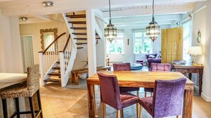 A spacious dining area with a wooden table and purple chairs, a staircase, and a view of the outdoors. - Enjoy the historic Tetenshof Marrakesch farmhouse in a quiet setting (Welt)