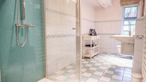 A bathroom with a glass shower enclosure, a white sink, and a tiled floor. - Enjoy the historic Tetenshof Marrakesch farmhouse in a quiet setting (Welt)