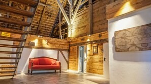 Een houten interieur met een rode bank, een ladder en een wereldkaart aan de muur.