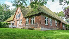 A traditional brick house with a thatched roof, surrounded by a well-maintained lawn. - Enjoy the historic Tetenshof Marrakesch farmhouse in a quiet setting (Welt)