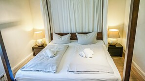 A neatly made bed with white linens and pillows, two bedside lamps, and a wooden headboard. - Enjoy the historic Tetenshof Marrakesch farmhouse in a quiet setting (Welt)