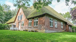 A traditional brick house with a thatched roof, surrounded by a well-maintained lawn. - Haubarg Tetenshof Jägerglück: A Historic Vacation Home for a Relaxing Getaway (Welt)