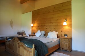 A bedroom with a wooden headboard, a bed with multiple pillows, a nightstand, and a bedside table with a lamp. - Haus Drischlag Vacation Rental (Ramsau bei Berchtesgaden)