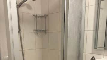 Eine Duschkabine mit Handbrause und einem an der Wand befestigten Ablagebrett.