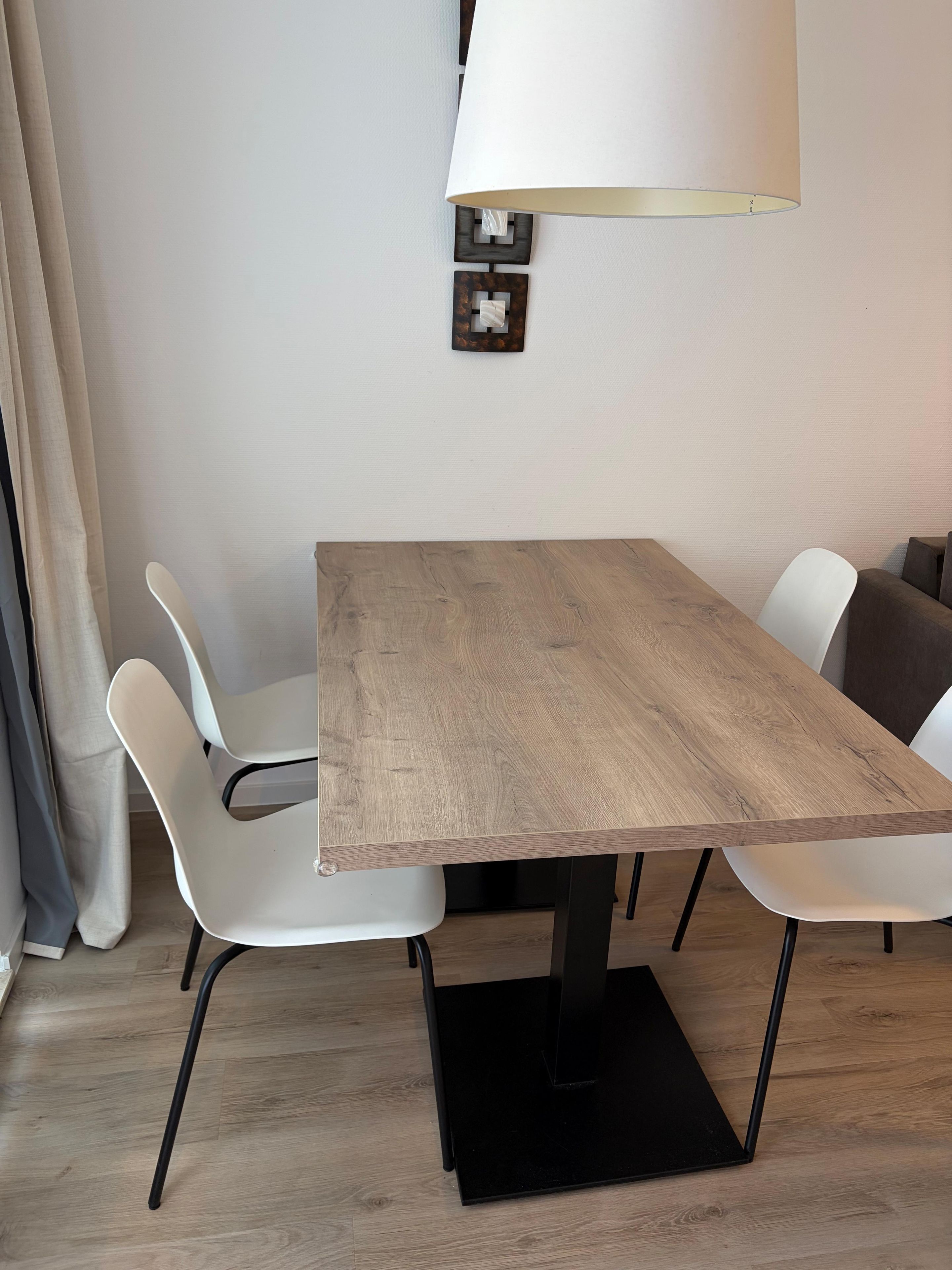 A dining area with a wooden table, white chairs, and a black floor lamp.