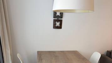 A dining area with a wooden table, white chairs, and a black floor lamp.
