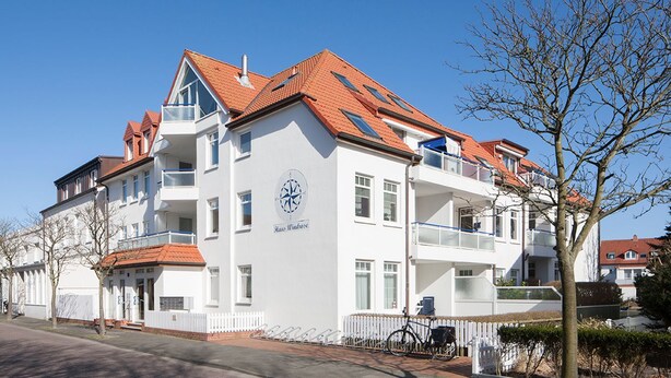 Ein mehrstöckiges Hotel mit weißer Fassade, rotem Ziegeldach und Balkonen.