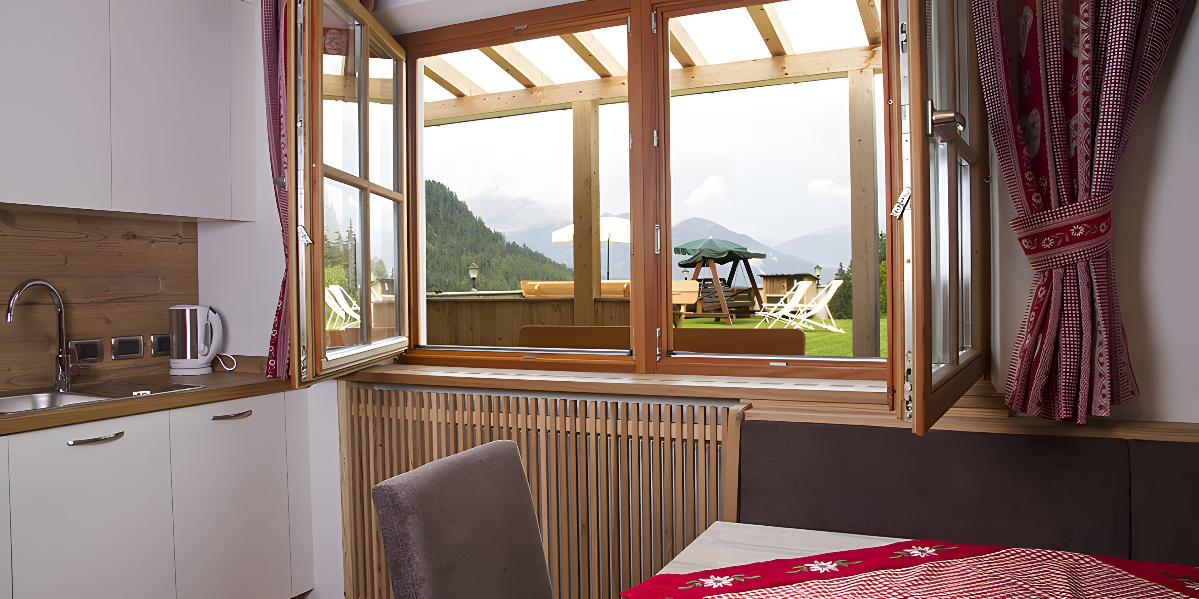 Habitación con vista a una terraza y montañas, un radiador, un lavamanos y una silla.