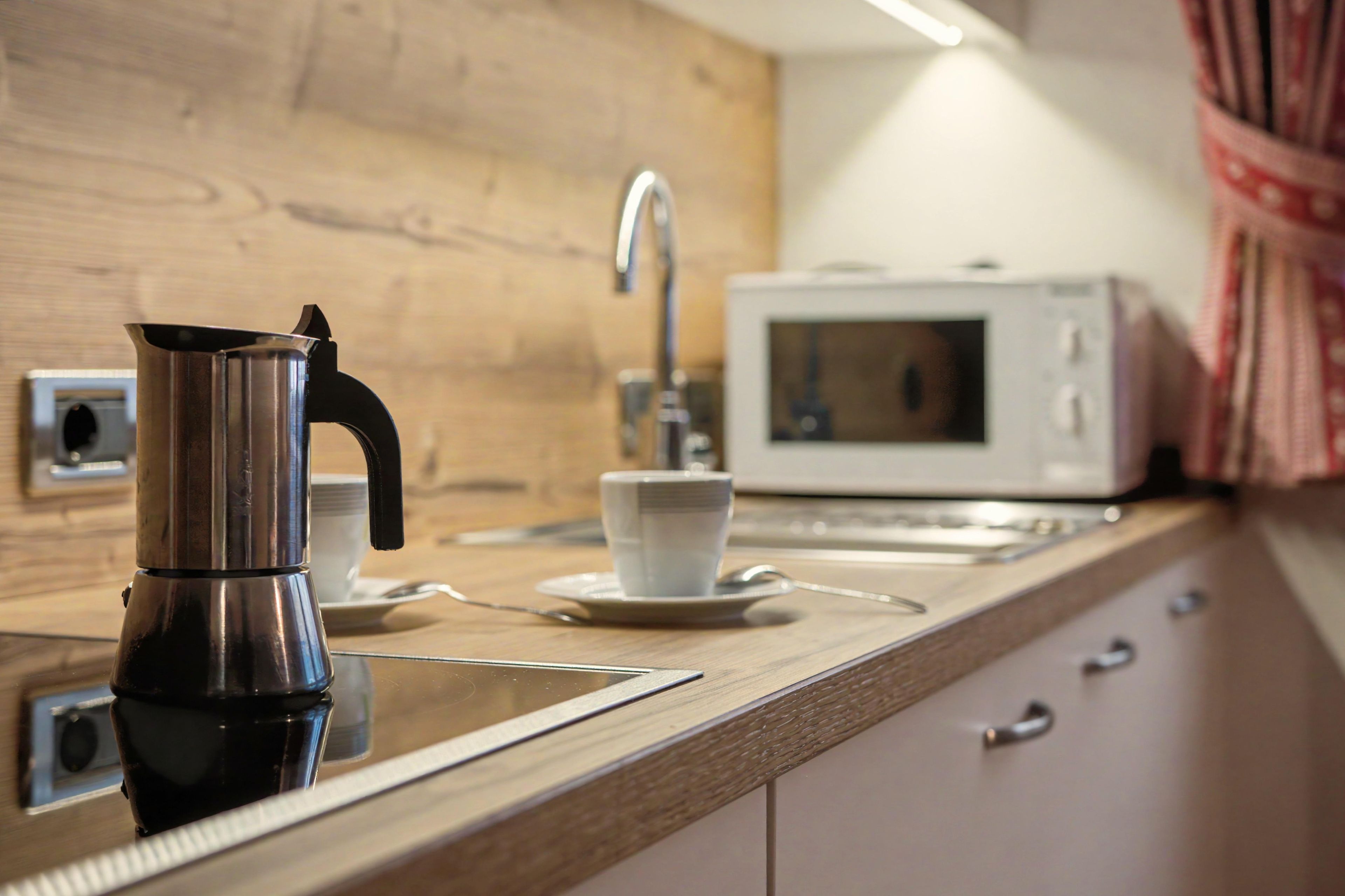 Una cucina con una macchina da caffè, un forno a microonde e una tazza sul bancone.